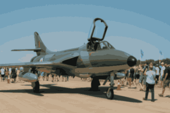 Crowd admiring a Hawker Hunter jet at an airshow under blue sky